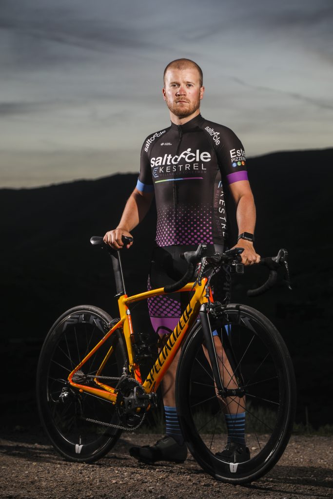 Sawyer Pangborn standing behind a bicycle wearing SaltCycle-Kestrel Wellness cycling kit.